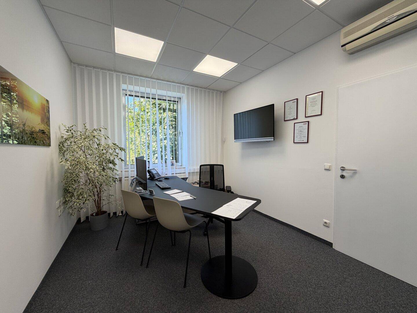 Helles Einzelbüro mit Schreibtisch, Bürostuhl, Klimaanlage und Blick auf die umliegende Natur.