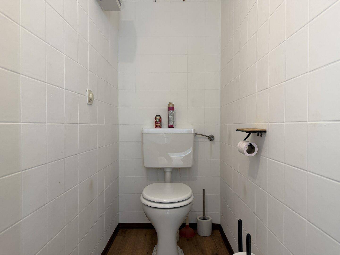 Separates WC mit weiß gefliesten Wänden und einer Standardtoilette.