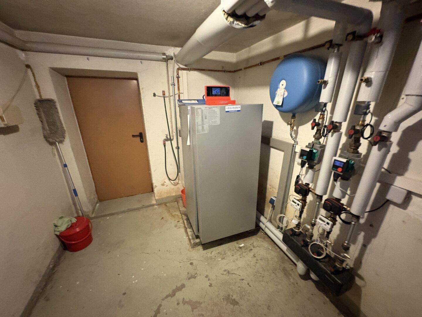 Kellerraum mit Heizungsanlage und Rohrleitungen, der als Technikraum dient.