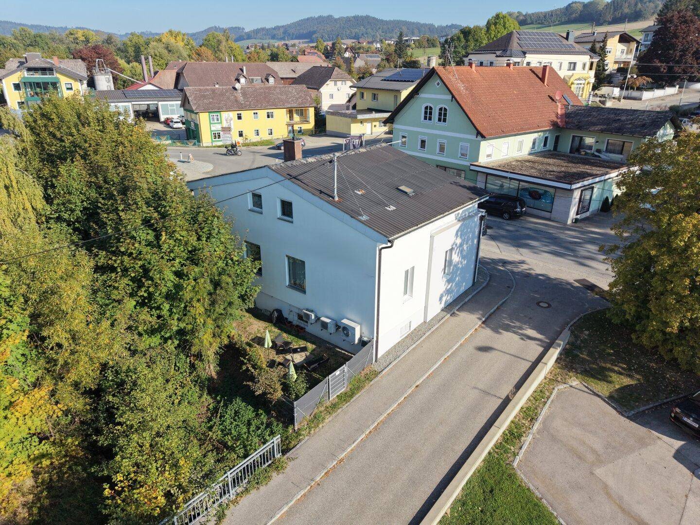 Rückseite des Gebäudes mit einem kleinen, gepflegten Gartenbereich und Sitzgelegenheiten im Freien.