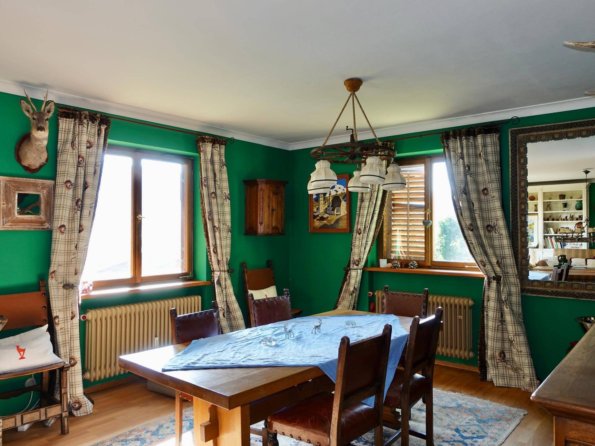 Gemütliches Esszimmer mit grünen Wänden, Holztisch und traditioneller alpiner Dekoration.