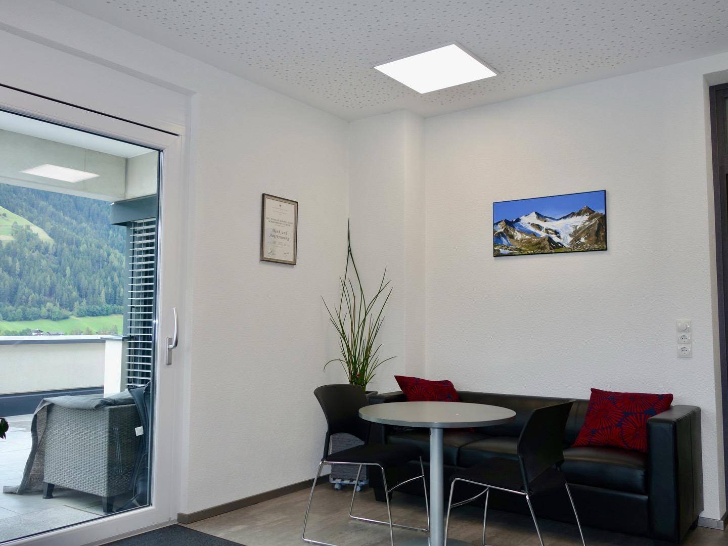Gemütlicher Loungebereich mit Sofa und Zugang zu einer Terrasse mit beeindruckendem Bergblick.