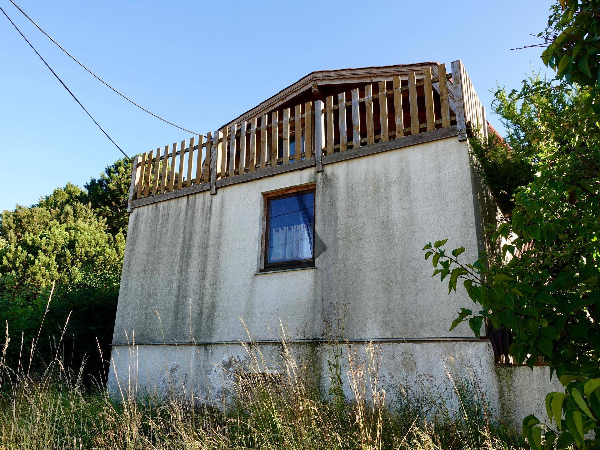 Äußere Ansicht eines kleinen Gebäudes mit Holzzaun und einfacher Fassade.