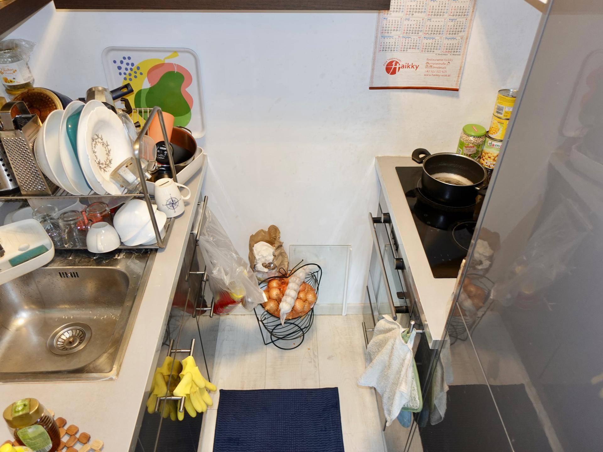 Kleine, funktionale Küchenzeile mit Spülbecken, Kochfeld und Stauraum.