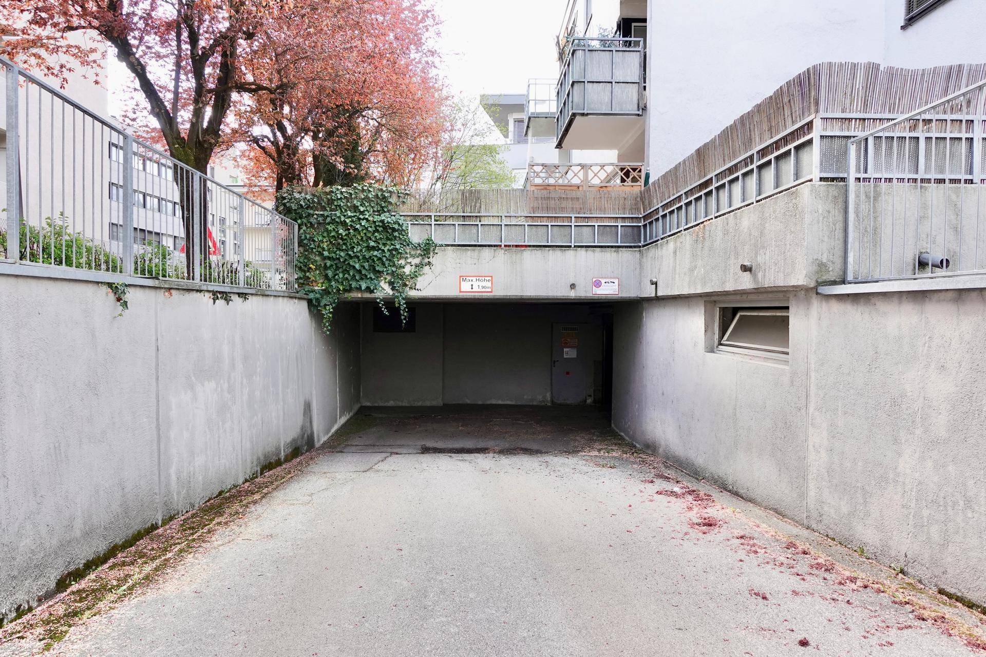 Einfahrt zu einer Tiefgarage unter einem Wohngebäude mit Betonwänden.