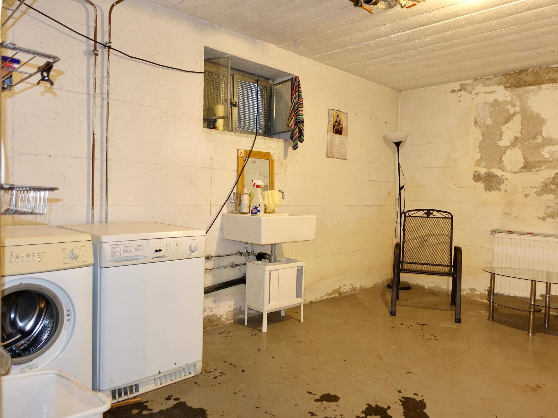 Praktischer Waschraum im Keller mit Waschmaschine, Trockner und Waschbecken.