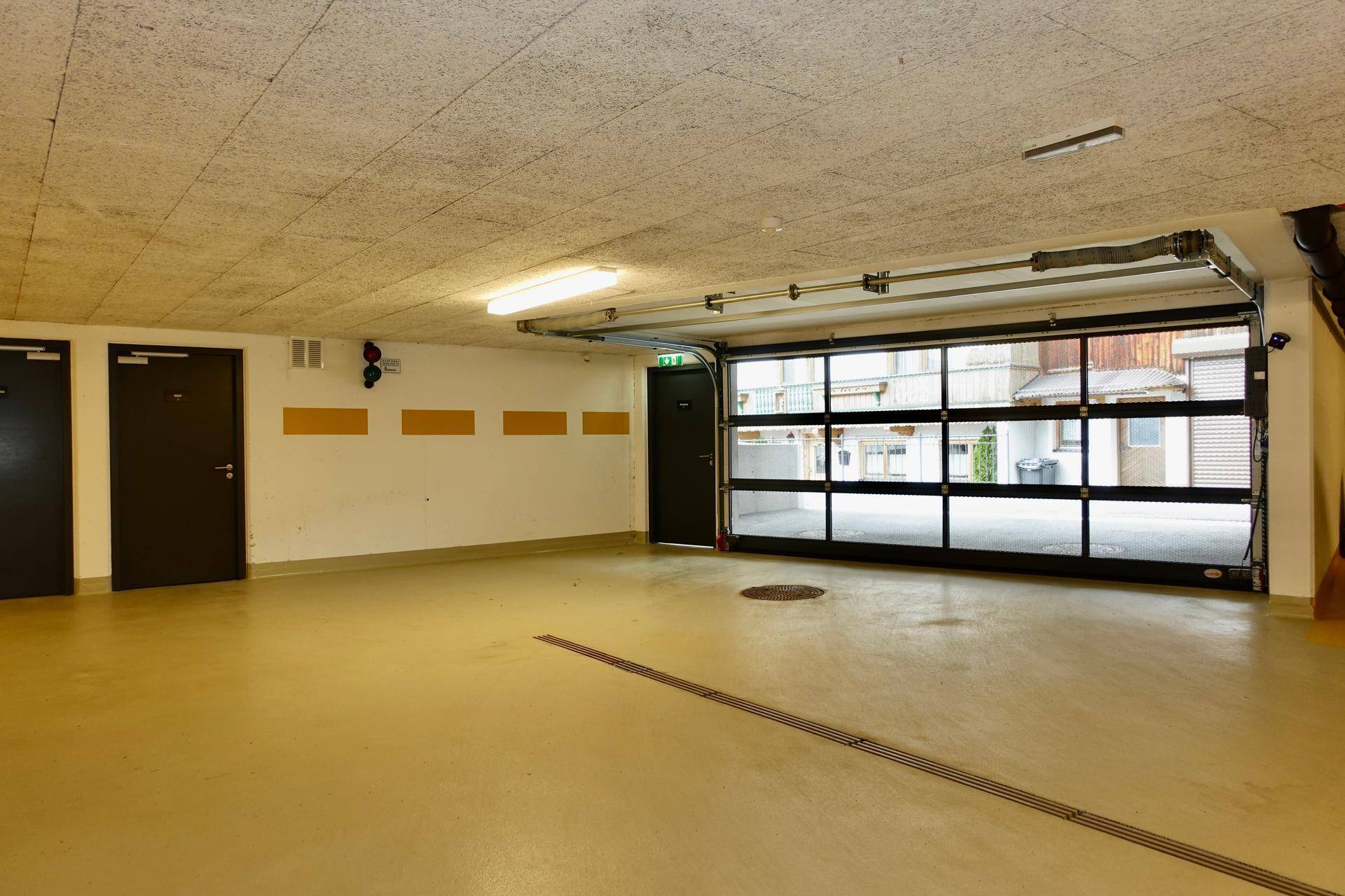 Geräumige Garage mit Rolltor, Zugangstüren und ausreichend Platz für Fahrzeuge.