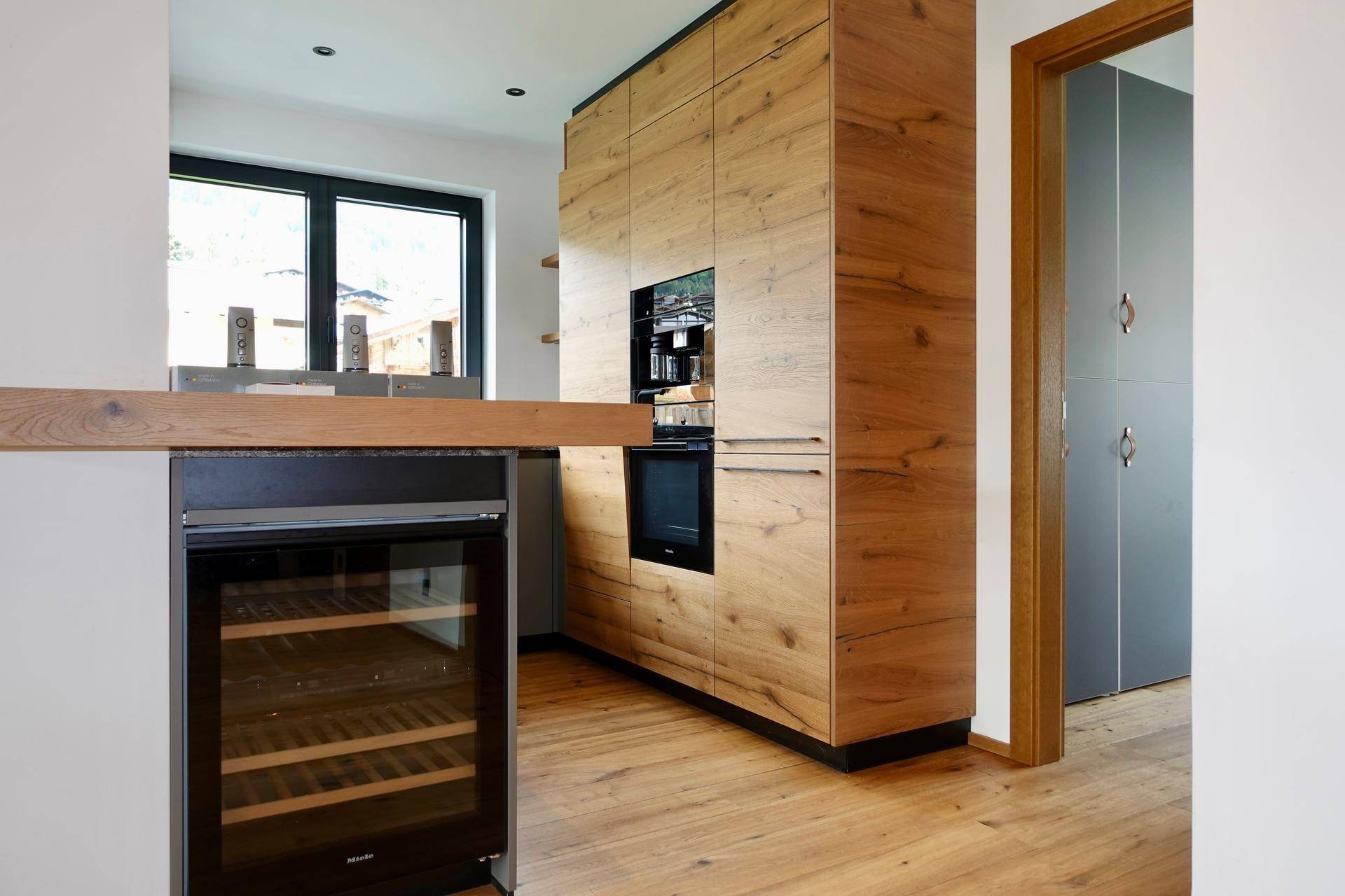 Moderne Holzküche mit integrierten Geräten, Weinkühler und Holzboden.