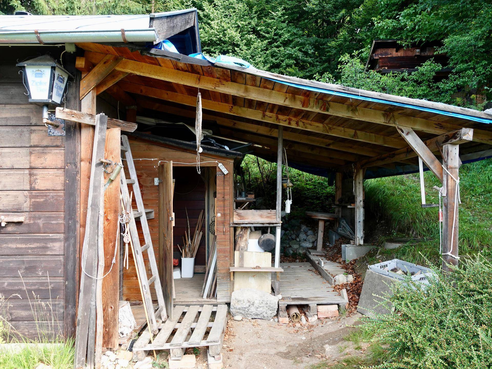 Überdachter Eingangsbereich oder Lagerfläche an der Seite der Holzhütte.