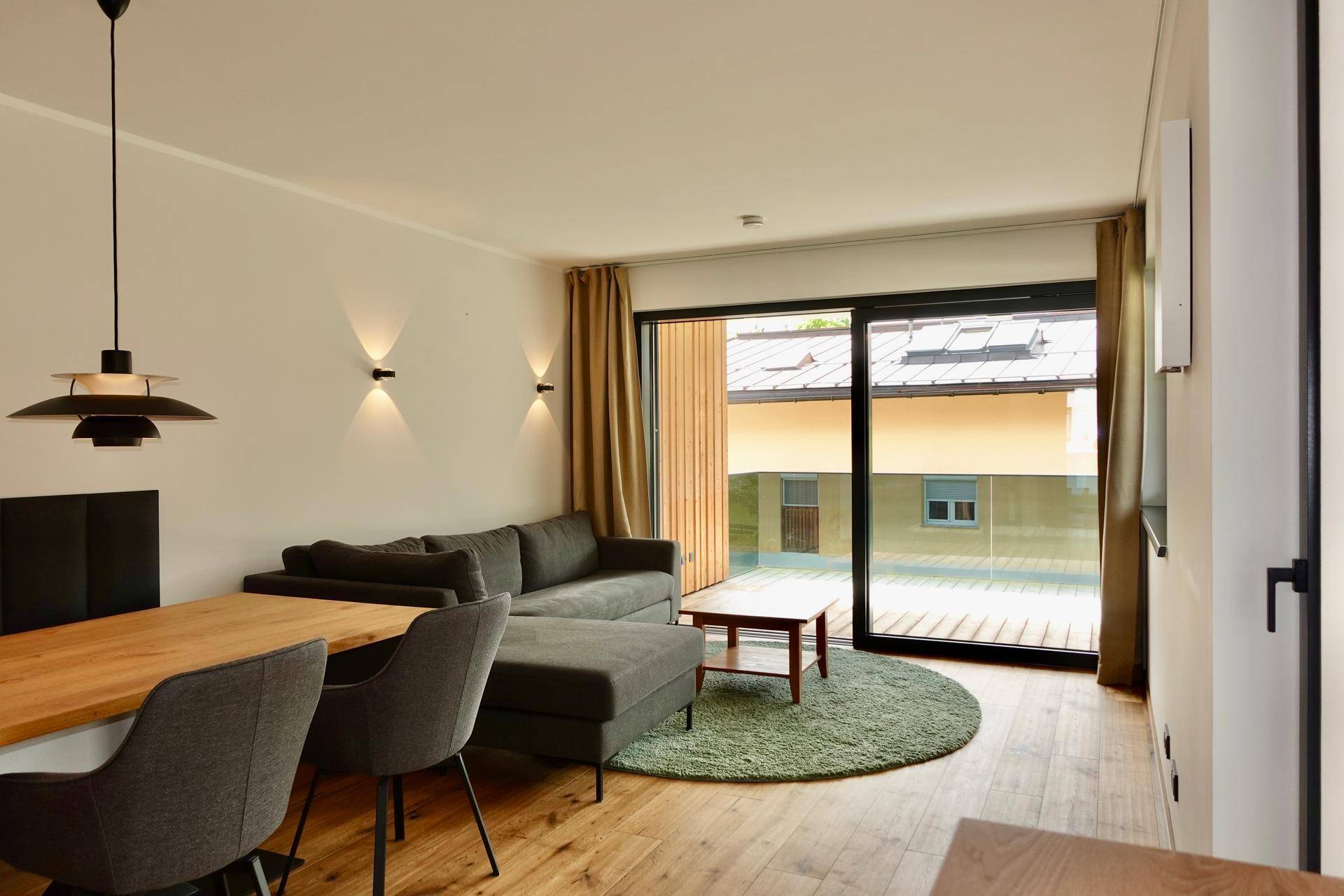 Heller Wohn-Essbereich mit Zugang zum Balkon, Holzboden und moderner Einrichtung.