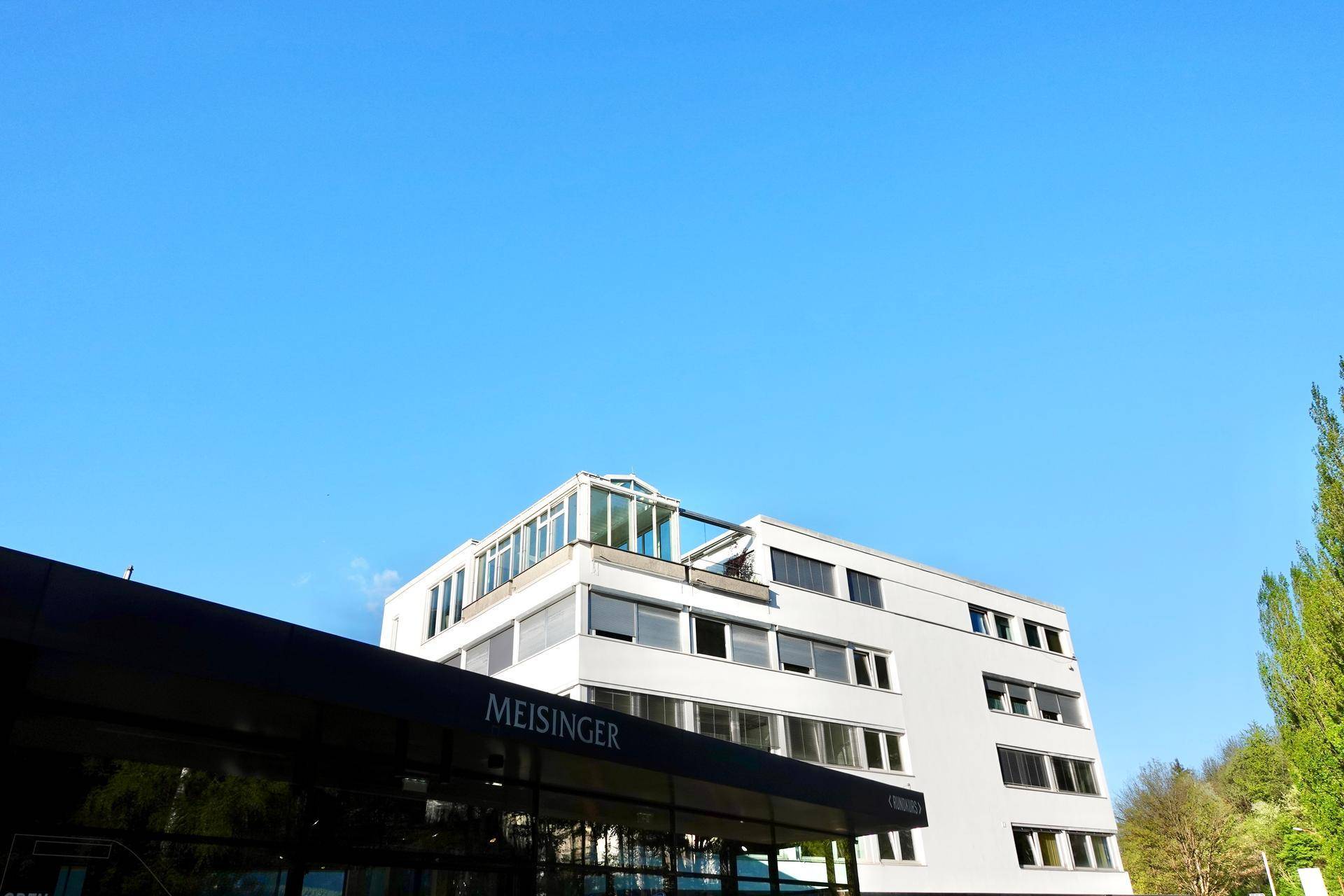 Moderne Architektur eines Geschäftsgebäudes mit großen Fenstern unter klarem blauem Himmel.