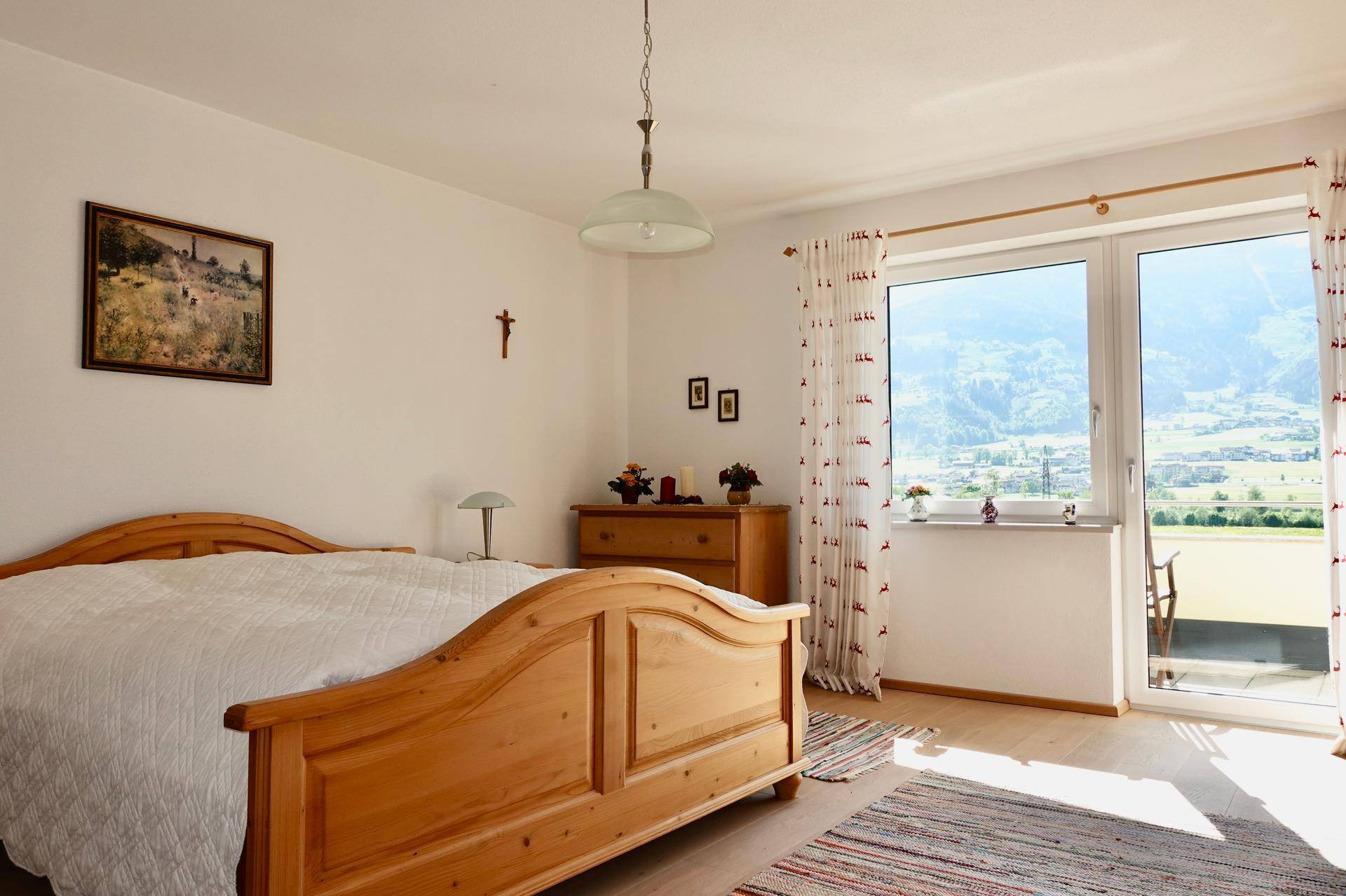 Gemütliches Schlafzimmer mit Holzbett, Holzboden und Balkonzugang.