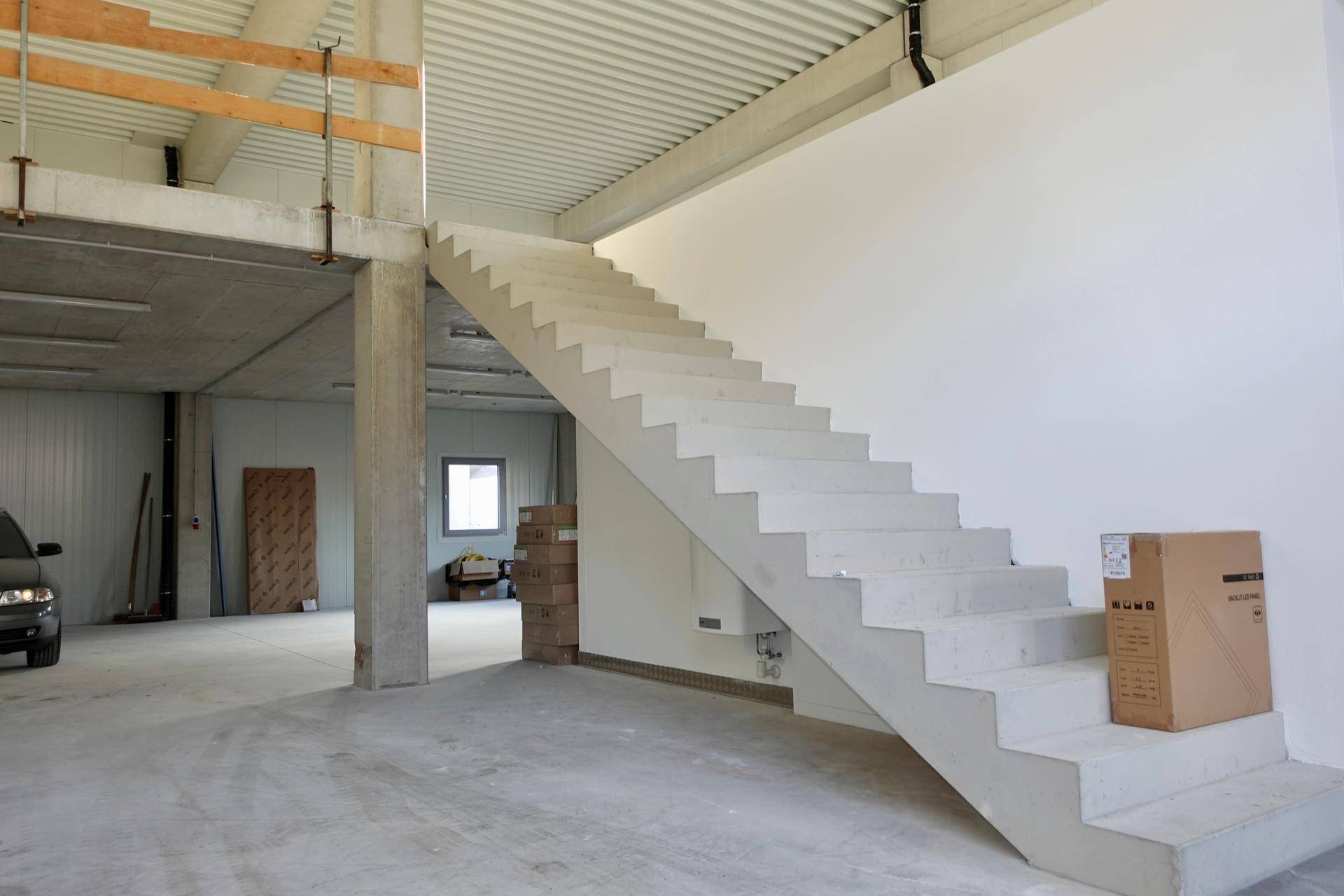 Großer Industrieraum mit einer massiven Betontreppe und hohen Decken, bereit zur Nutzung.