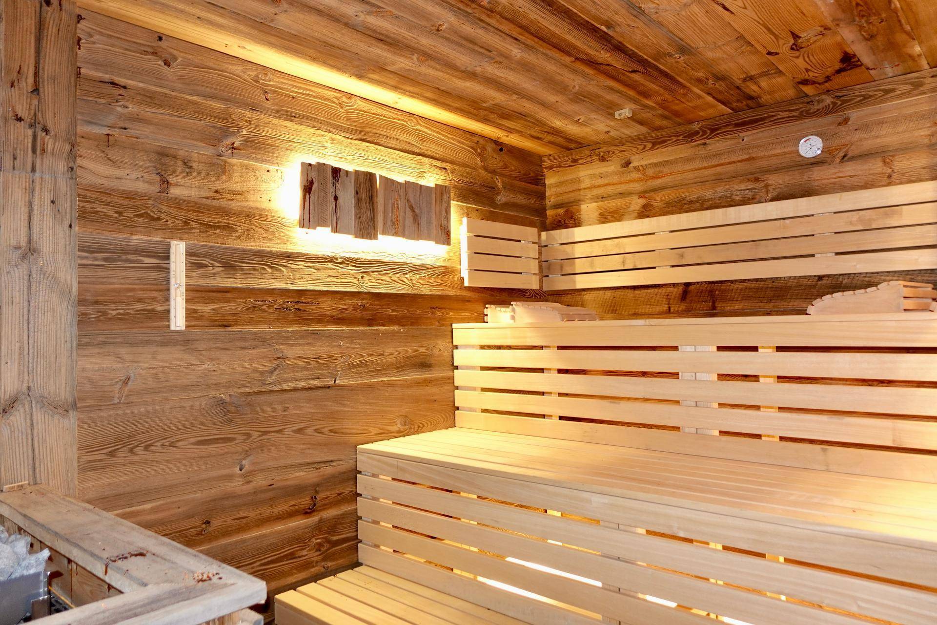 Gemütliche Holzsauna mit traditionellen Bänken und indirekter Beleuchtung für Entspannung.