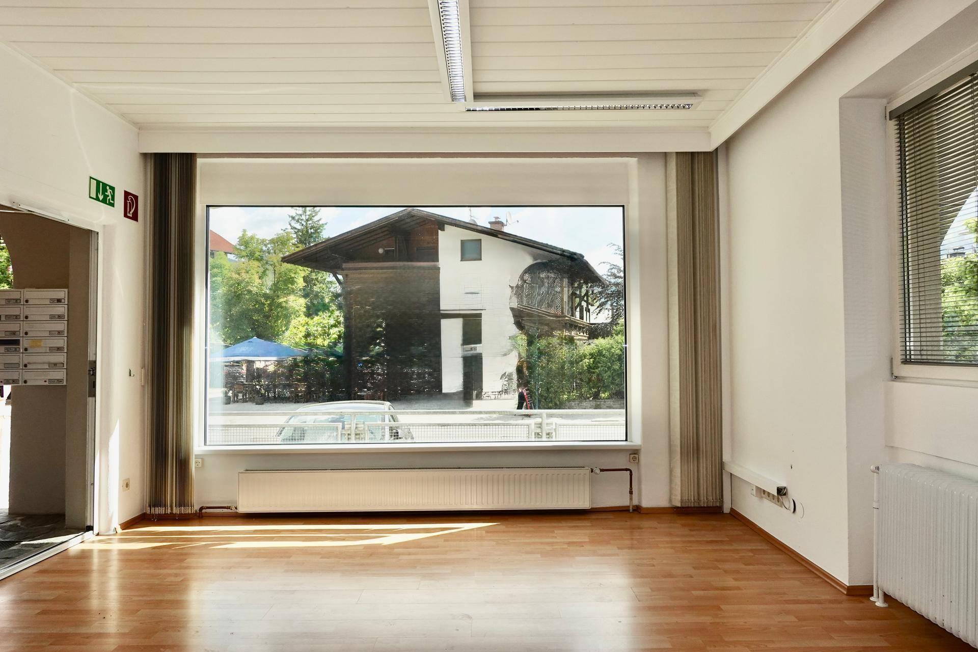 Geräumiger Innenraum mit großem Fenster, das einen Blick auf die Straße und ein gegenüberliegendes Gebäude bietet.