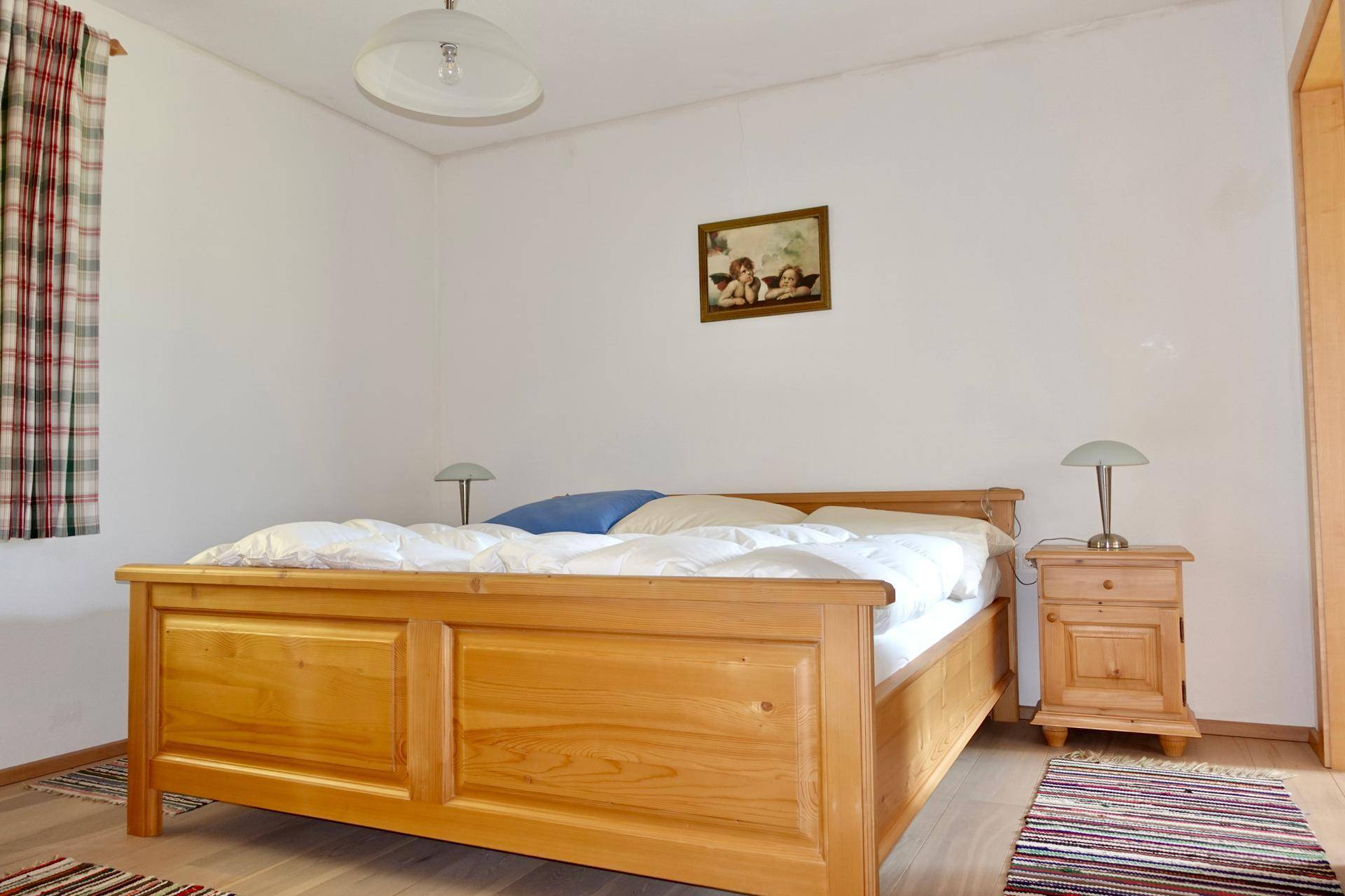 Schlafzimmer mit Doppelbett, Holzboden und Fenster.