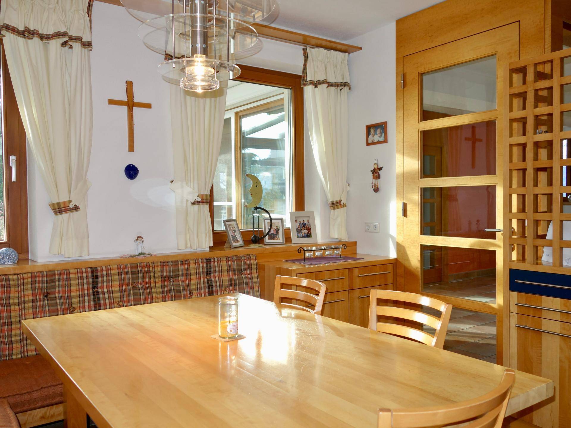 Heller Essbereich mit Holztisch, Eckbank und traditionellen Dekorationselementen.