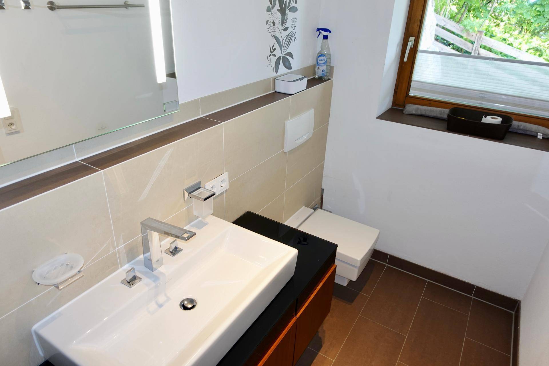 Helles Gäste-WC mit modernem Waschbecken, Wand-WC und Fenster für Tageslicht.