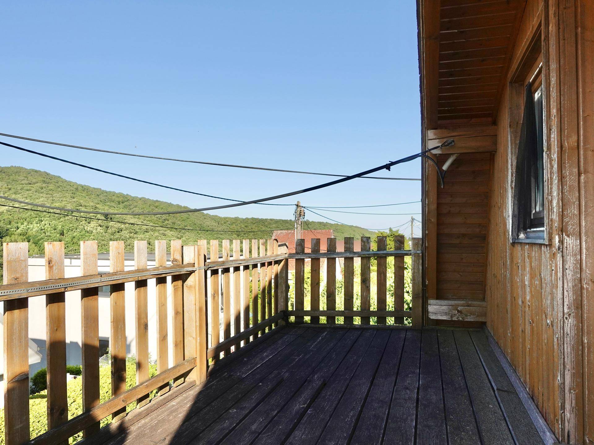 Holzbalkon mit Geländer und weitem Blick über die grüne Landschaft.