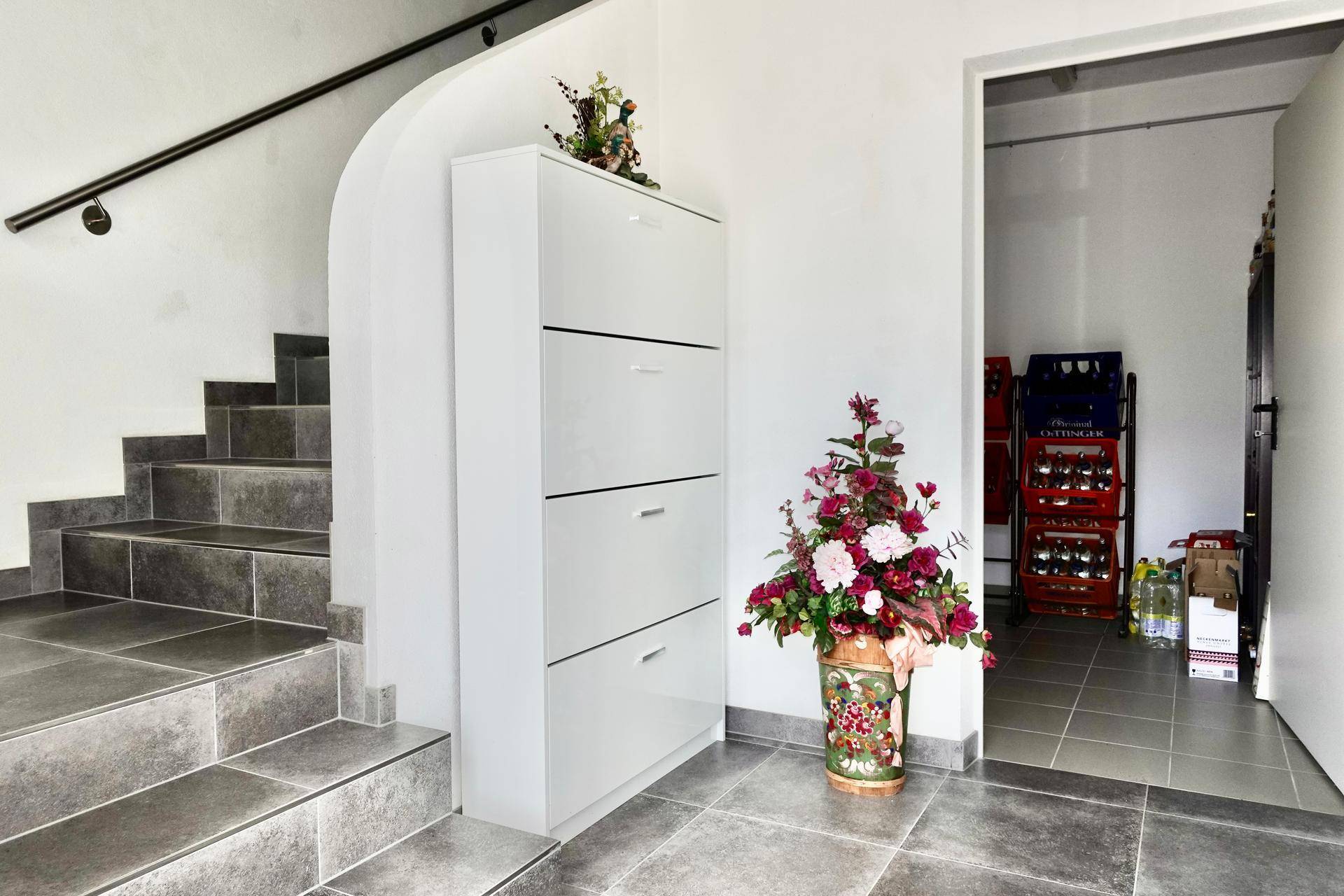 Eingangsbereich mit Treppe, Schuhschrank und Fliesenboden.