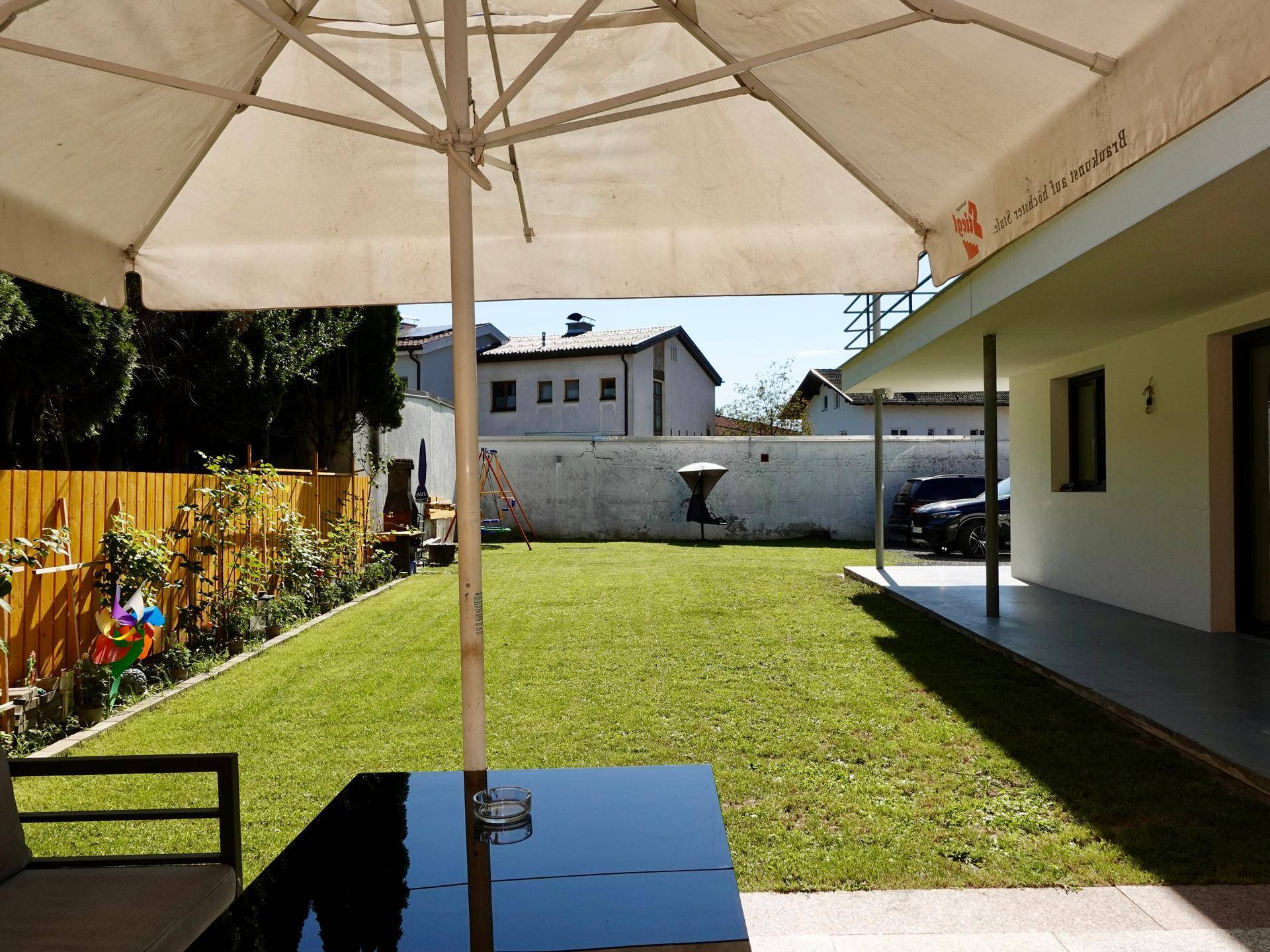 Gepflegter Gartenbereich mit Rasenfläche, Sonnenschirm und Blick auf das Haus.