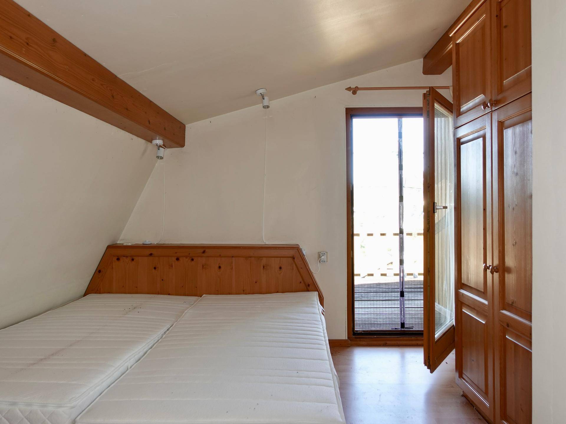 Schlafzimmer mit zwei Betten, Holzschränken und direktem Zugang zum Balkon.