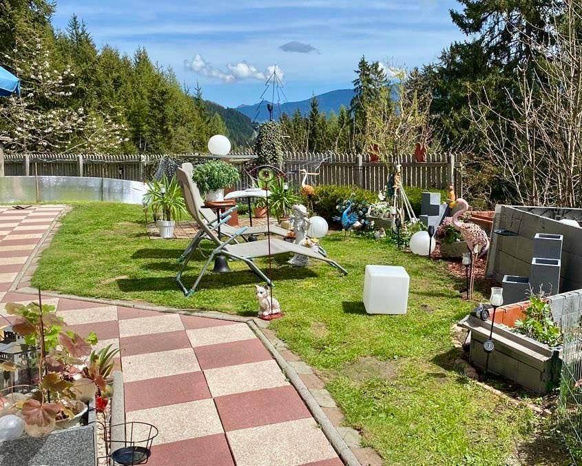 Gepflegter Gartenbereich mit Rasenfläche, gepflasterten Wegen und verschiedenen Dekorationen.