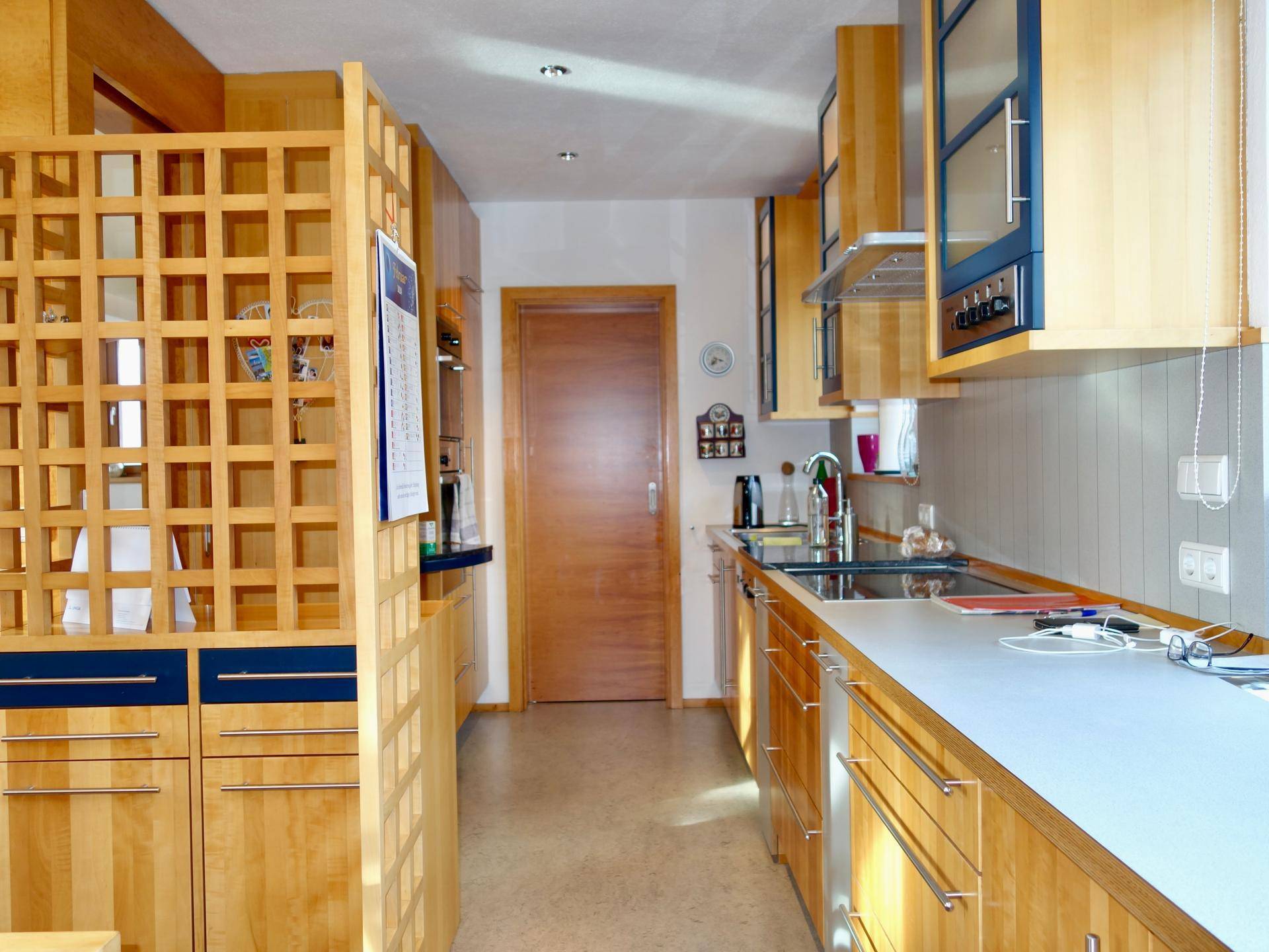 Funktionale Küche mit Holzschränken, blauen Akzenten und integrierten Geräten.