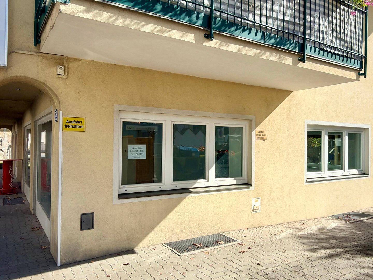 Nahaufnahme der Gebäudefassade im Erdgeschoss mit Fenstern und einem Eingangsbereich.