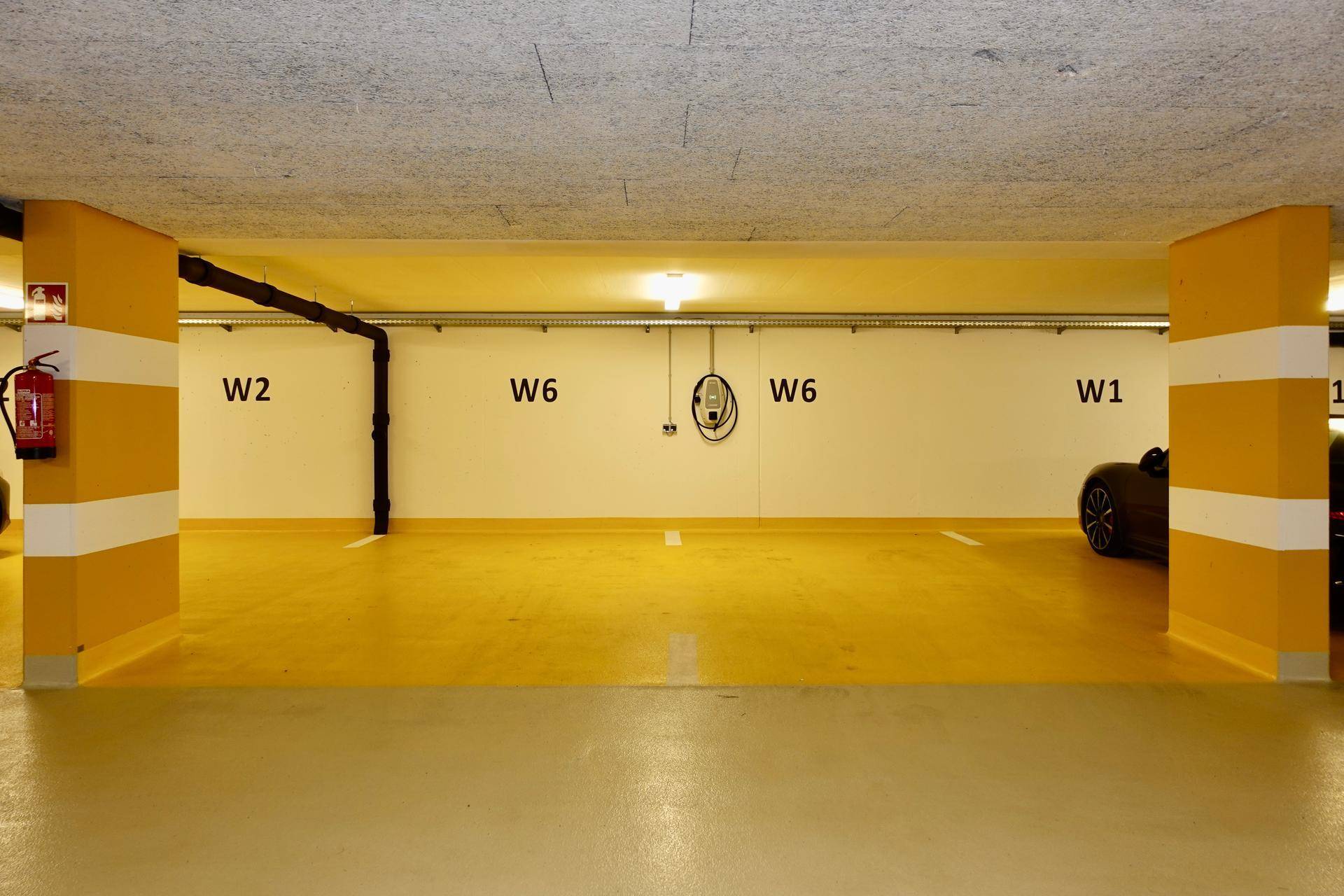 Tiefgarage mit markierten Stellplätzen und Ladestation für Elektrofahrzeuge.