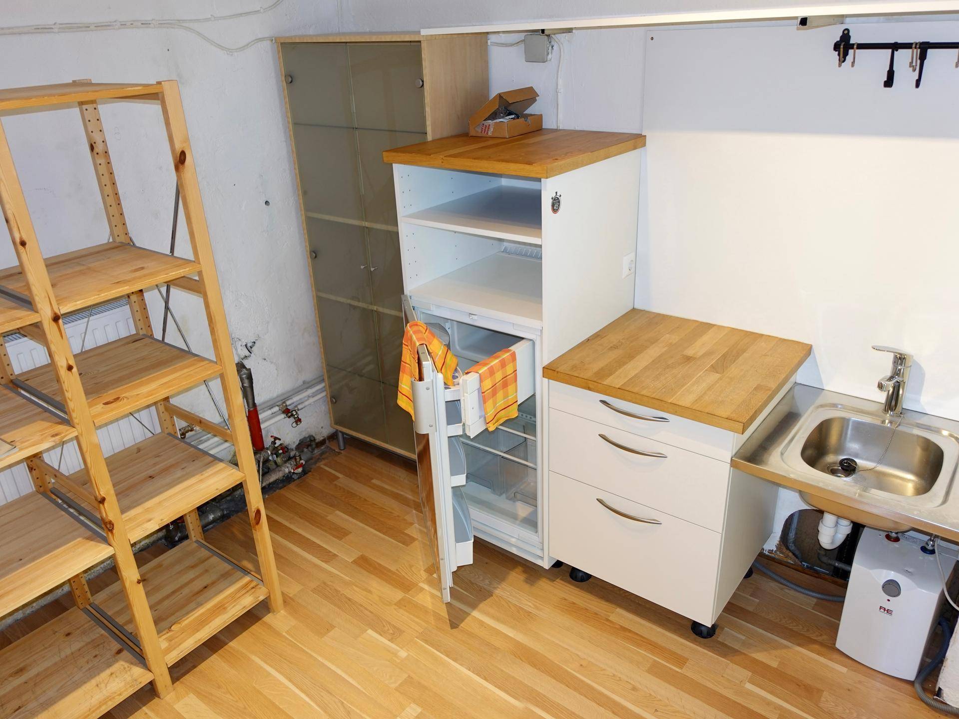 Funktionaler Abstellraum mit Holzregalen, einer kleinen Spüle und einem Schrank mit Holzplatte, praktisch eingerichtet.
