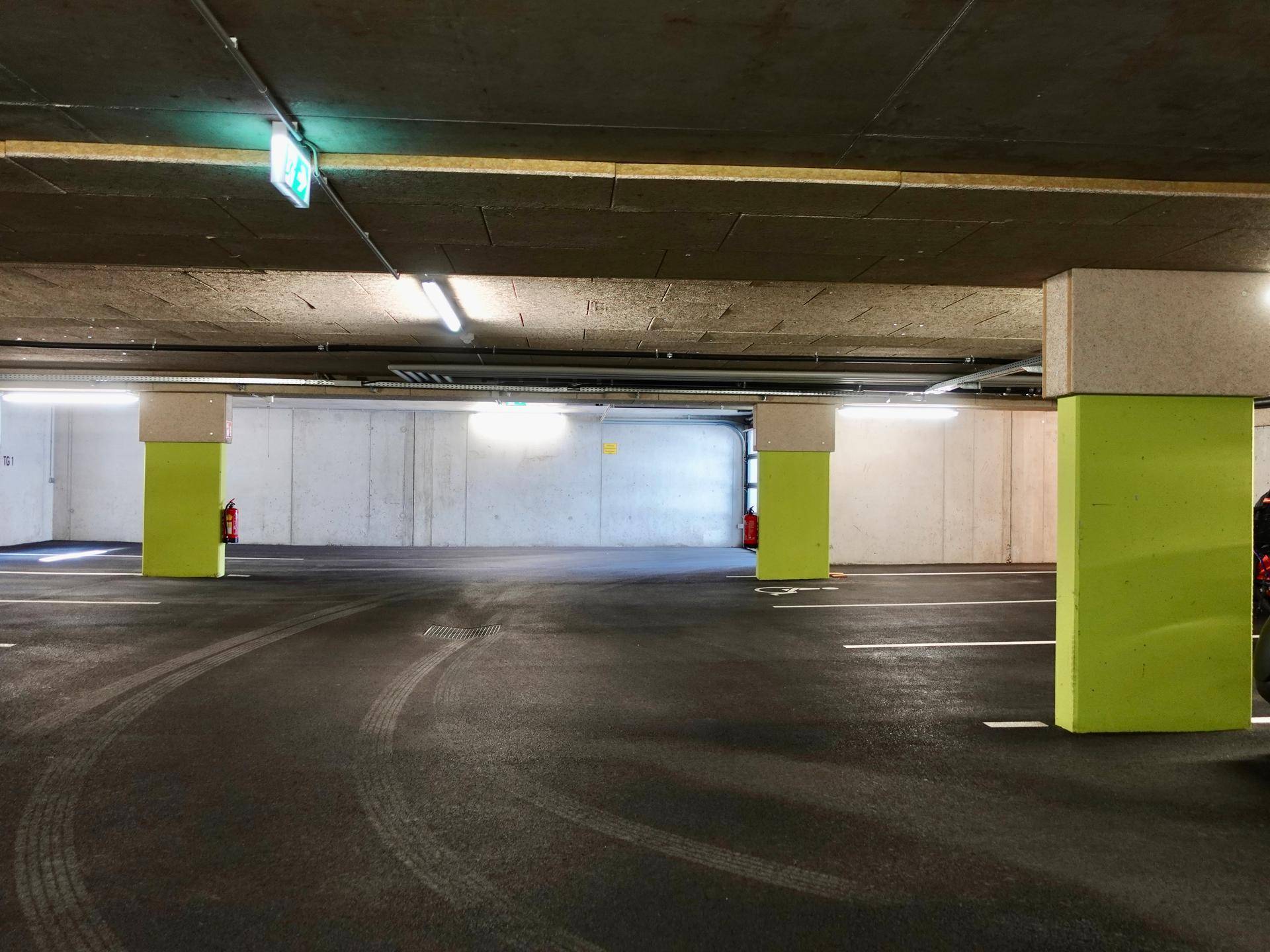 Geräumige Tiefgarage mit mehreren leeren Parkplätzen und hellgrünen Stützpfeilern.