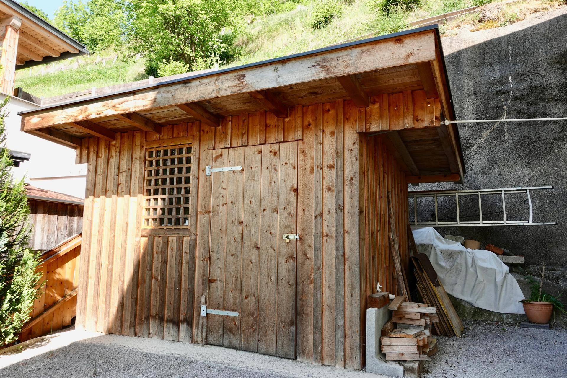 Rustikaler Holzschuppen mit Fenster und Holztür im Außenbereich.