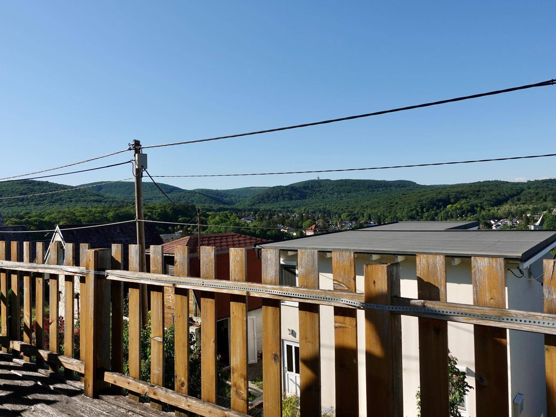 Blick vom Balkon auf grüne Hügel und die umliegende Wohnbebauung.