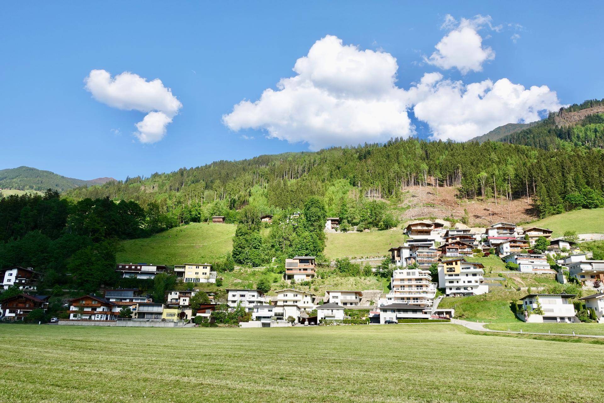 Weitläufige Landschaft mit grünen Hügeln und Häusern in der Ferne.