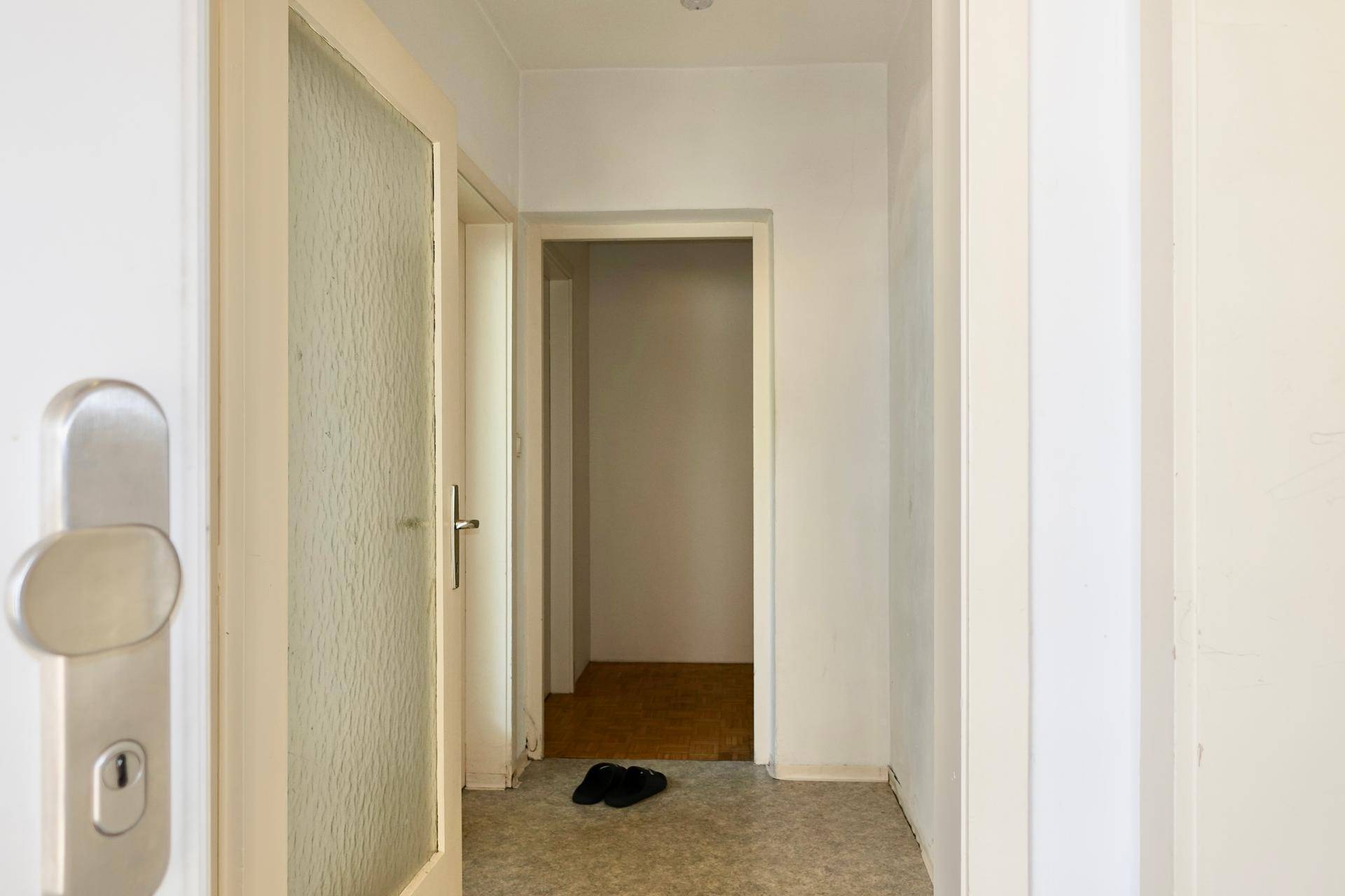 Heller Flur mit weiß gestrichenen Wänden und einer Tür mit Milchglas.
