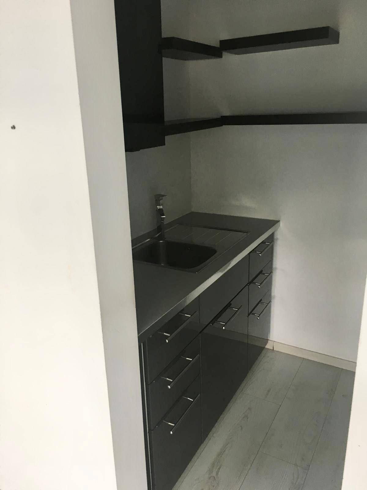 Detailansicht der Küchenzeile mit Spülbecken, Unterschränken und offenen Regalen.