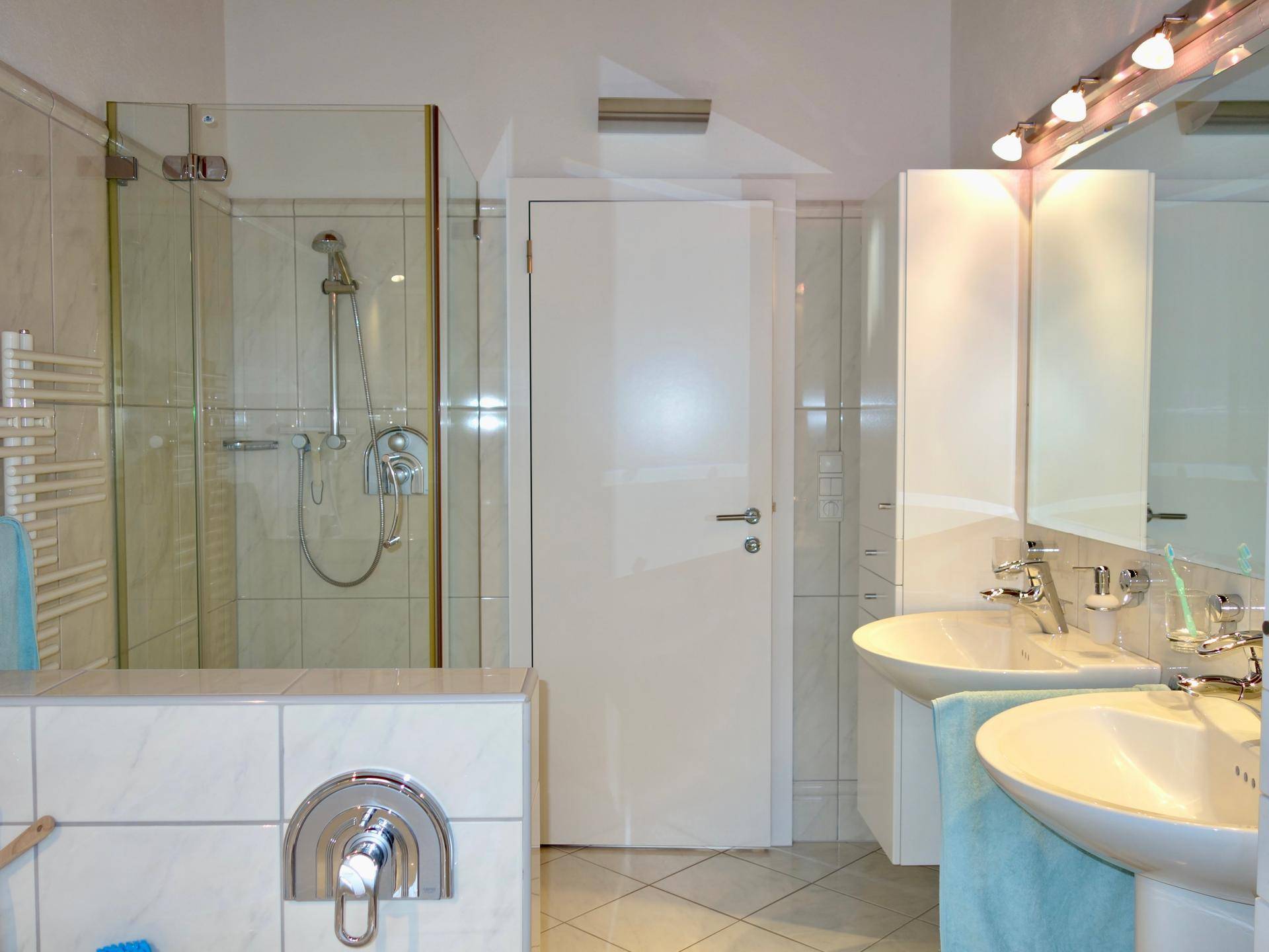 Modernes Badezimmer mit Doppelwaschbecken, Duschkabine und beheiztem Handtuchhalter.