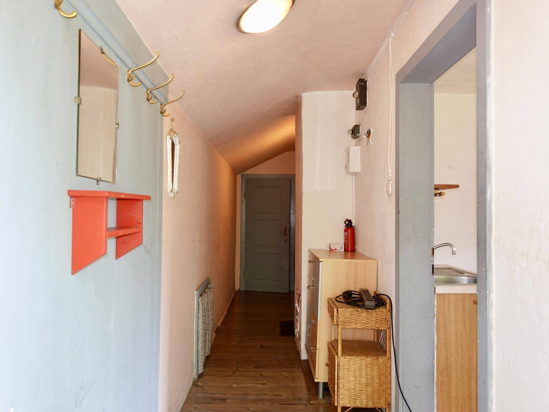 Langer Flur mit Holzfußboden, Garderobe und Zugang zu weiteren Räumen.