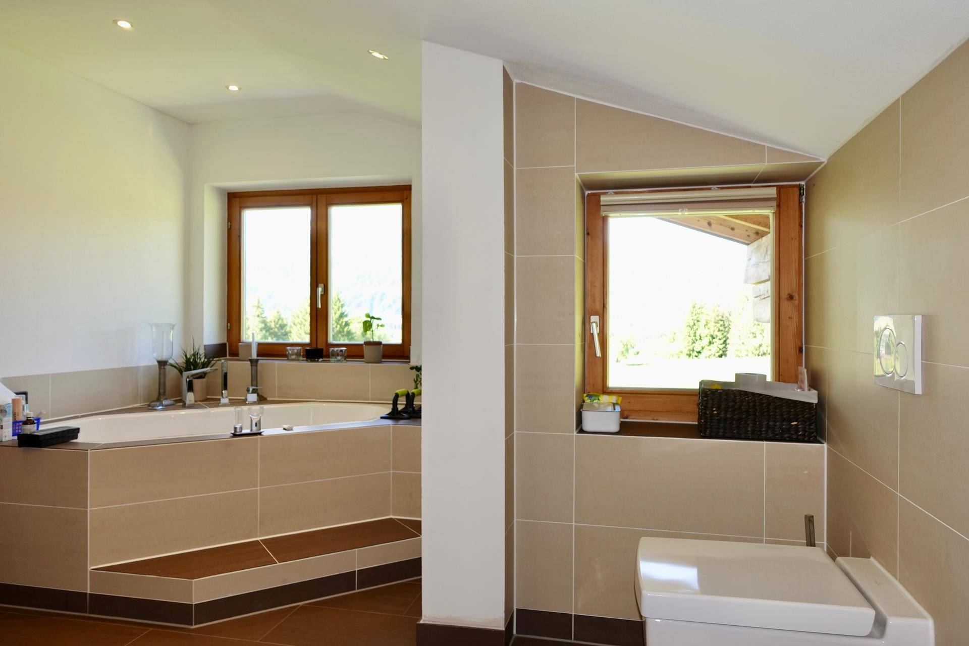 Geräumiges Badezimmer mit Eckbadewanne, Wand-WC und Fenster, hell und modern gestaltet.