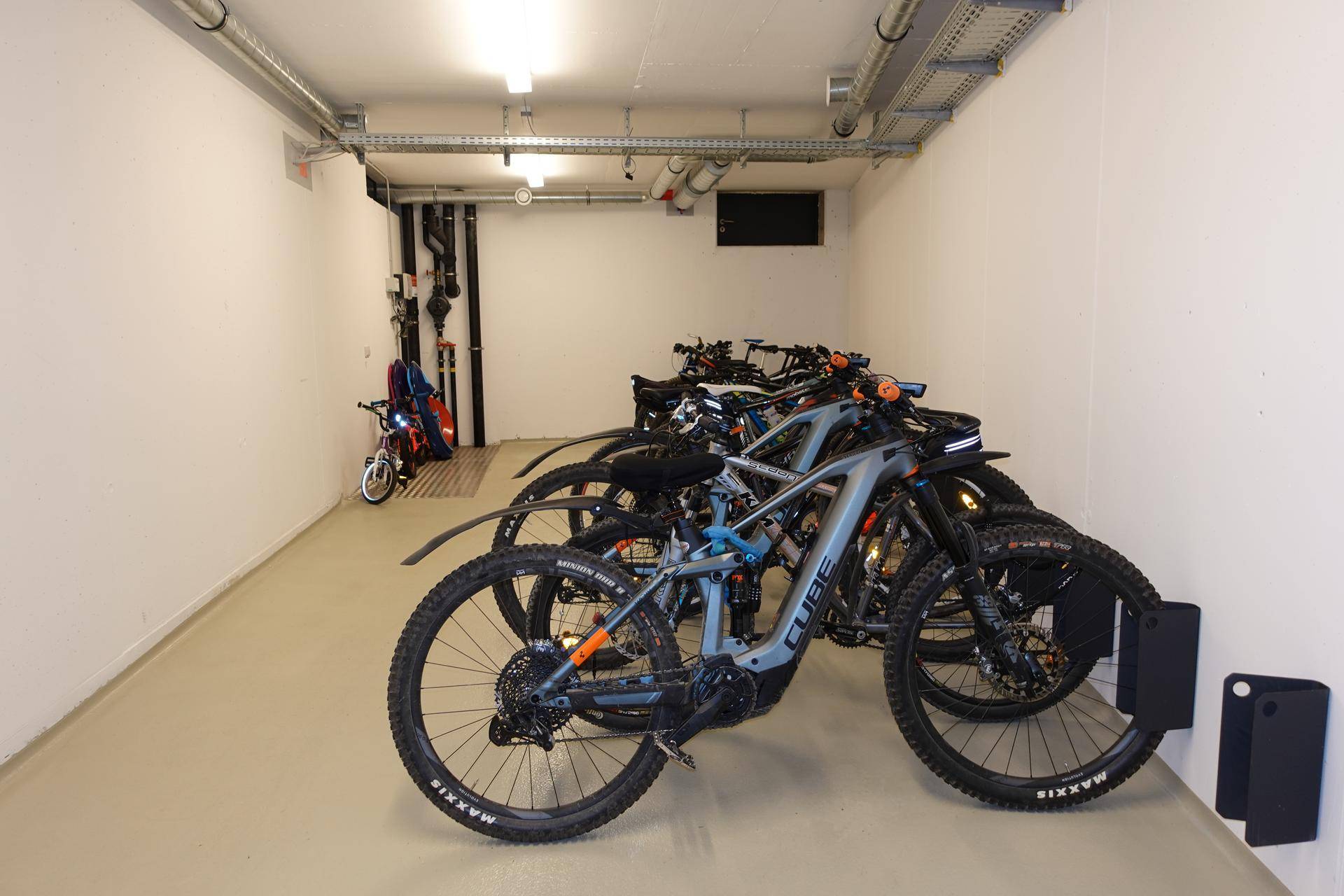 Fahrradraum mit mehreren Fahrrädern und Wandhalterungen für sichere Aufbewahrung.
