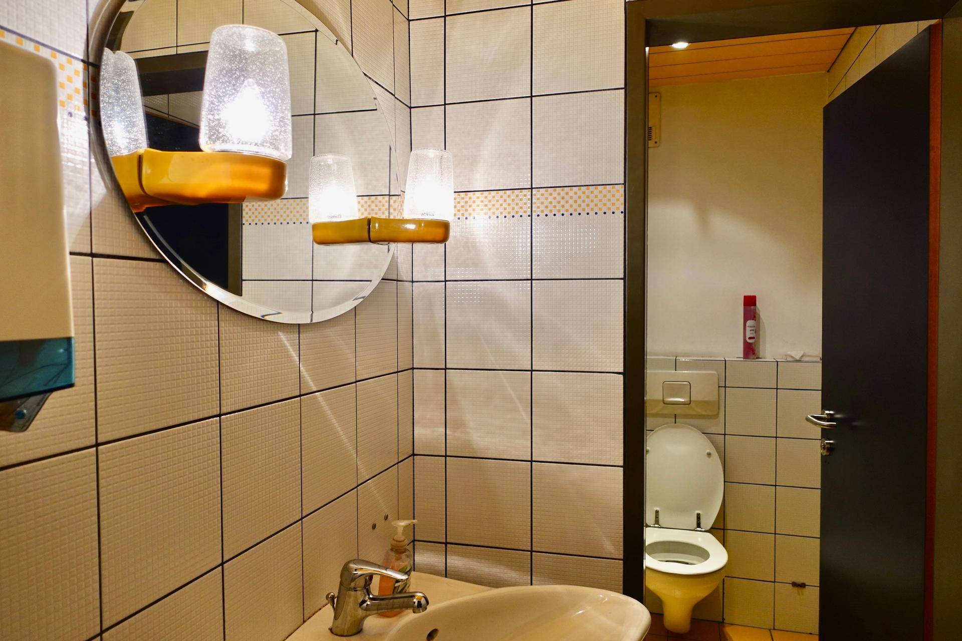 Kleine Gästetoilette mit Fliesenwänden, Waschbecken und WC in hellem Design.