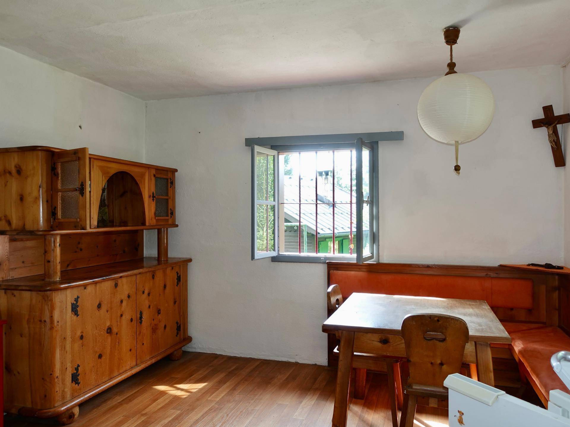 Gemütlicher Essbereich mit traditionellen Holzmöbeln und Blick ins Grüne durch das Fenster.