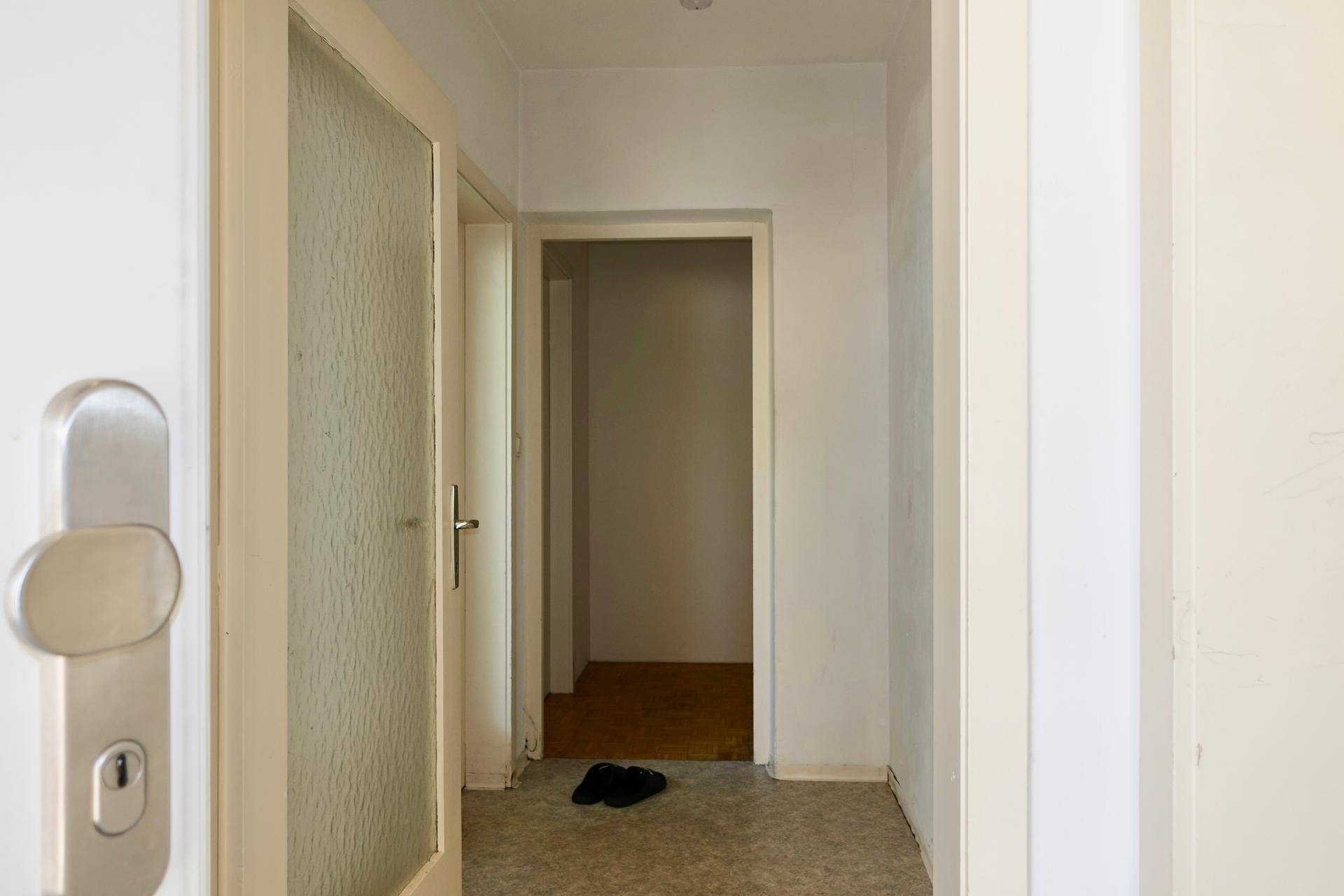 Heller Flur mit weiß gestrichenen Wänden und einfacher Bodengestaltung.