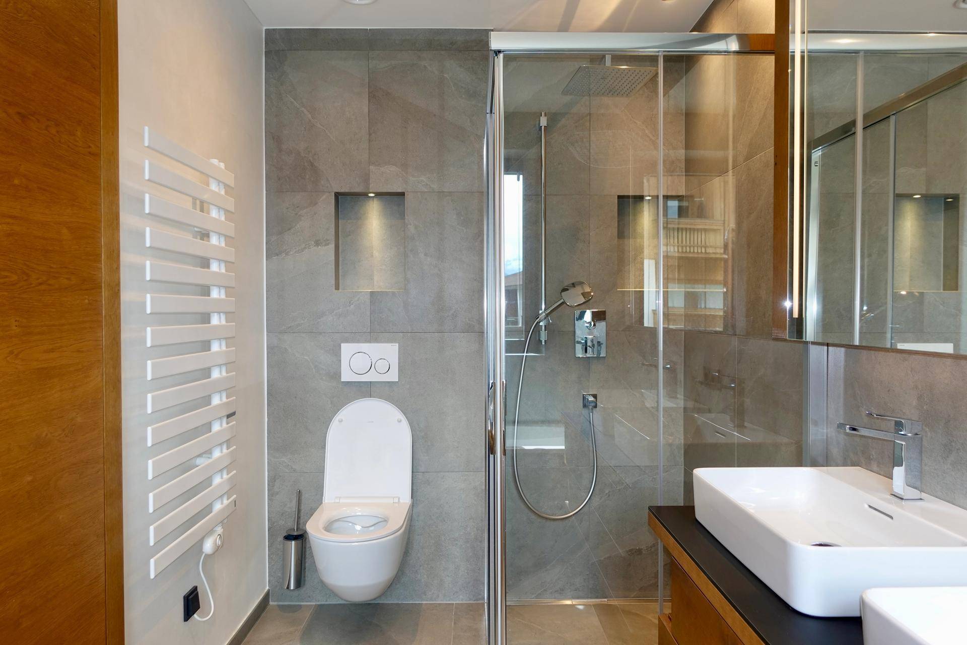 Modernes Badezimmer mit Dusche, Wand-WC, Waschbecken und beheiztem Handtuchhalter.