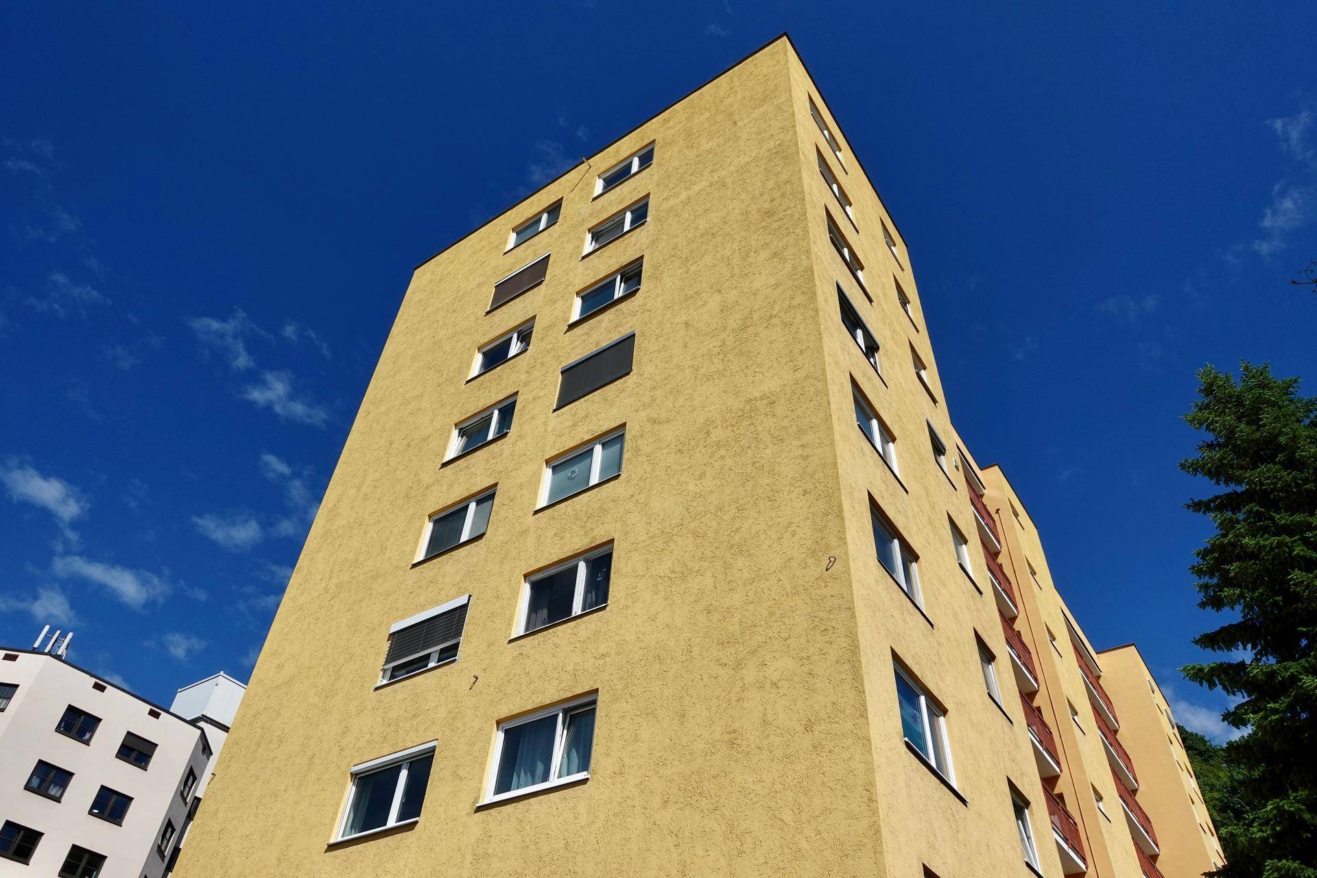 Hohes Gebäude mit gelber Fassade und vielen Fenstern unter klarem blauem Himmel.