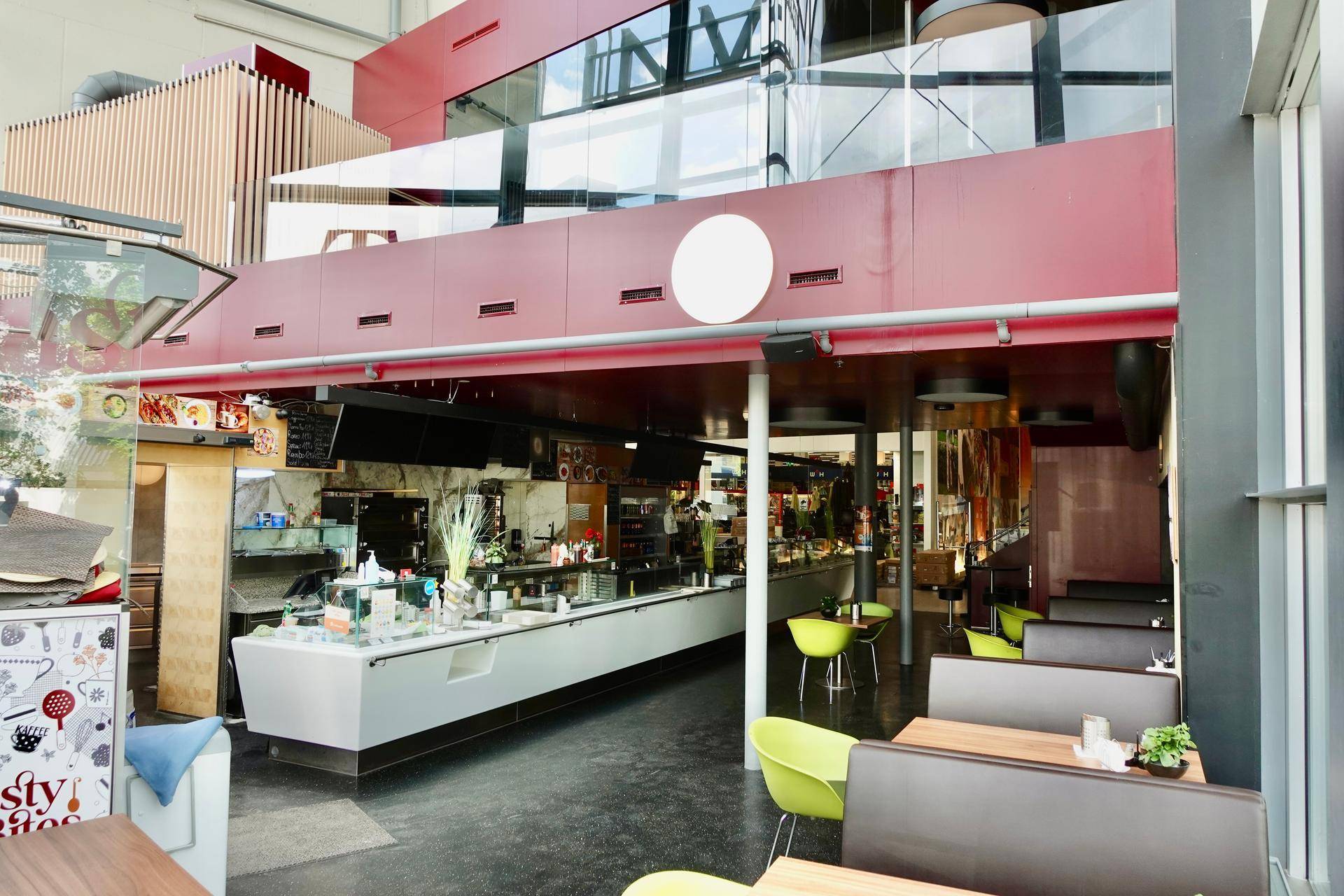 Geräumiger Restaurantbereich mit langer Theke, Essbereichen und einer Galerie im modernen Stil.