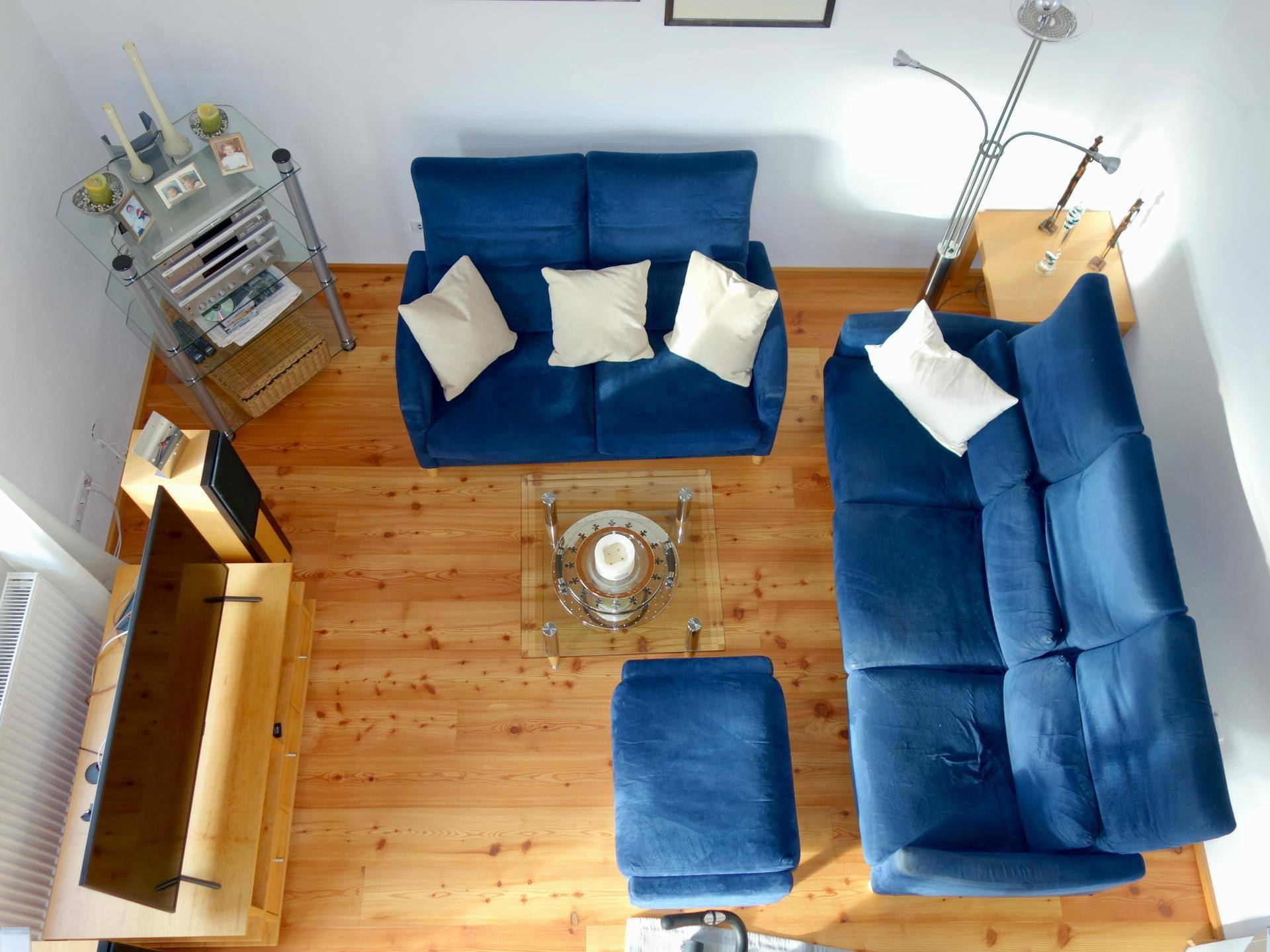Wohnzimmer von oben gesehen mit blauen Sofas, Holzboden und minimalistischer Einrichtung.