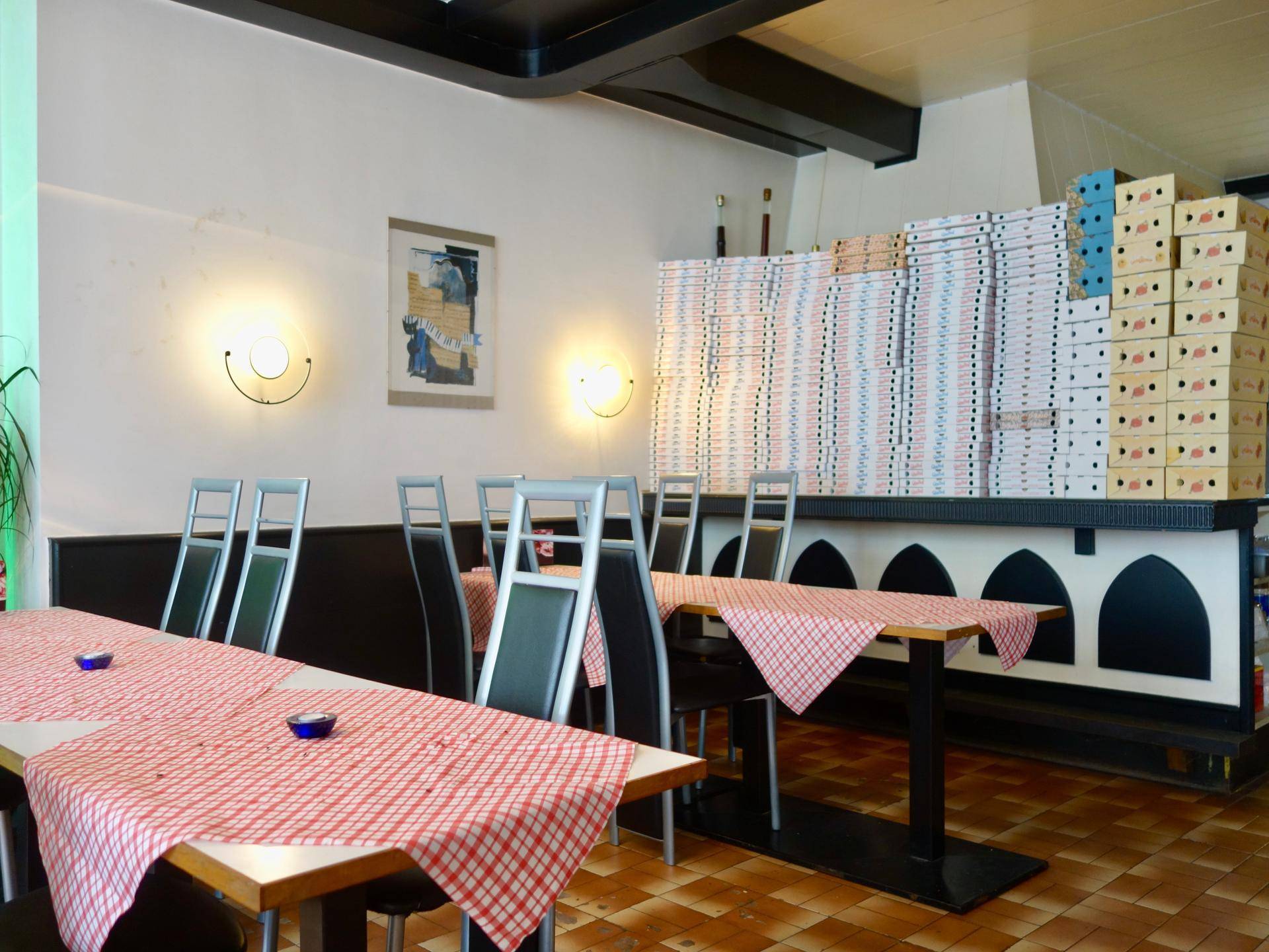 Gemütlicher Restaurantbereich mit Tischen, Stühlen und karierten Tischdecken, bereit für Gäste.