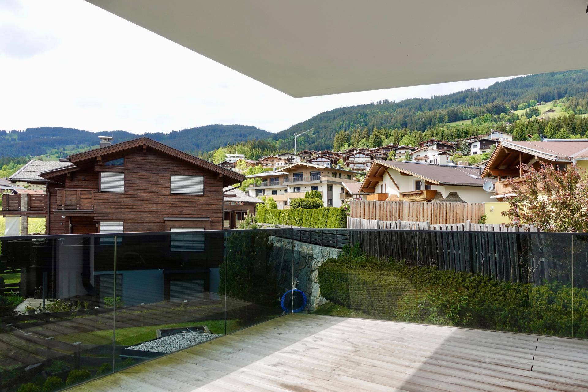 Balkon mit Holzboden, Glasbrüstung und weitem Blick über die alpine Umgebung.